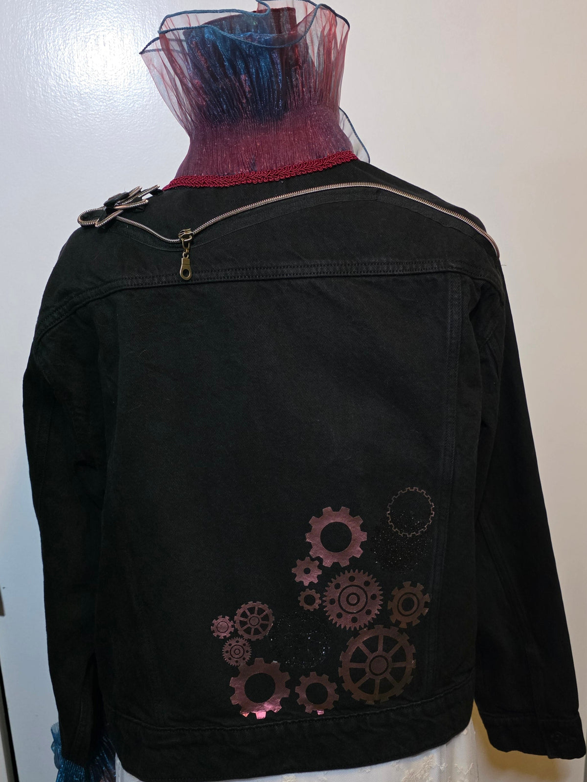 Back black denim jacket featuring dramatic teal and red organza ruffles, zipper flower, vintage buttons and steampunk gear details